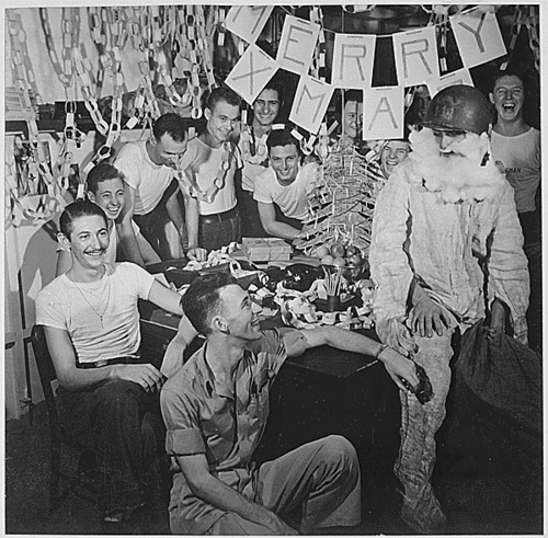 Image description: Personnel on the USS Lexington celebrate Christmas with make-shift decorations and a firefighting, helmeted Santa Claus. Photo taken in December 1944.
Photo from the National Archives