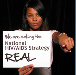 woman holding sign 'Facing AIDS by making the National HIV/AIDS Strategy REAL.'