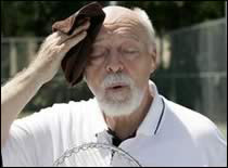 Photograph of elderly man wiping his forehead with a wet towel.
