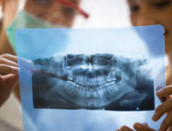 Two dentists examine an X-ray of a patient's mouth.