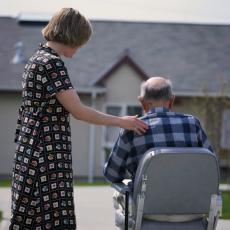 Photograph of a woman caring for a senior man in a scooter