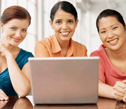 3 mujeres sonrientes delante de un ordenador
