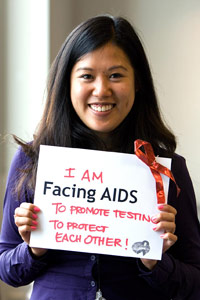 Woman smiling hold sign that says 'I am facing AIDS to promote testing to protect each other!