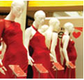 Several mannequins are wearing formal red dresses on display with name tags to identify which celebrity wore each outfit and which designer created each dress.