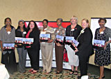 8 women in Sacramento, California, in a Champions training class, stand holding their speaker kits.