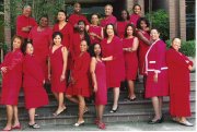 A crowd of women of varying ethnicities, ages, and body types wearing red dresses and red skirts pose on stairs.