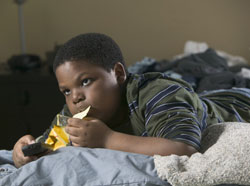 photo of a boy eating chips and watching TV