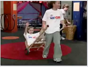 Screenshot of video showing a child pulling another child on a handcart