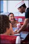 A teen worker waits on two women at a diner