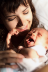 a woman smiles while holding a fussy infant