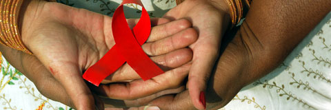 Red AIDS ribbon resting in two hands