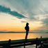 A woman standing on a dock looking at the sky.