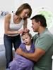 Image of a mother performing a lice check on her daughter while she sits in her father's lap.