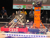Robots from Antelope Valley High team 2339 and Lancaster High team 399 balance on the tilting bridge at the conclusion of a match at the San Diego FIRST regional competition