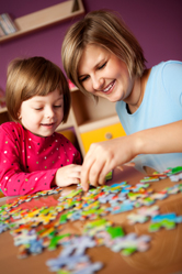 A mother and daughter work on a puzzle together.