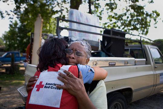 red cross volunteer hugs disaster survivor