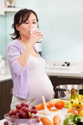 A pregnant woman drinks a glass of milk.