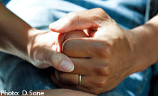 A photograph of an adult female hand holding an adult male hand