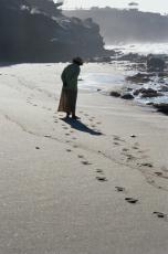 Fotografía de una mujer caminando por la orilla del mar