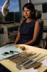 Fotografía de una paciente en la oficina del dentista con instrumentos dentales en una bandeja en primero plano