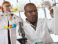 Photo of a male scientist in foreground holding test tube and pipette, female researcher in back.