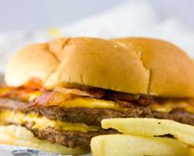 Copyrighted photo of a greasy bacon cheeseburger with french fries.