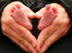 Photo of an adult's hands holding the baby's feet.