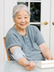 Photo of an old woman managing her heart health with a blood pressure cuff.