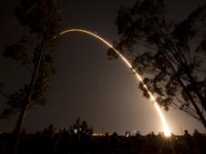 Delta II rocket arcs across the dark sky after launch.