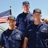Three members of the Coast Guard with American flag