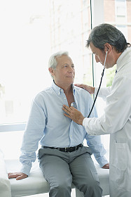 Picture of physician examining male patient with stethoscope.