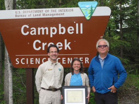 Stacey Shriner posing with the Science Center director and SCA Alaska Regional Director in front of the Science Center sign.