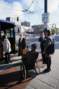 A group of people waiting to get on a bus, one in a wheelchair