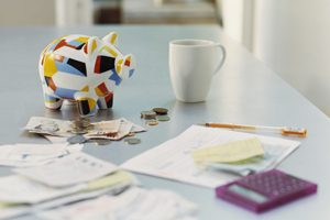 bills, calculatory, money, piggy banks, and mug on table