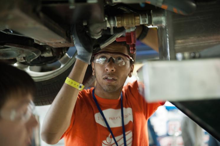 A North Carolina State University student works on an EcoCAR vehicle at the Year 3 finals last year in Milford, MI. | Energy Department photo. 
