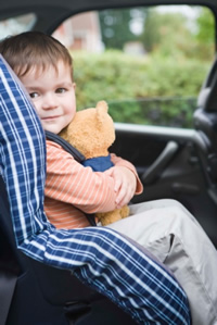 Photo: young boy with a teddy bear in a child safety seat