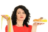 Woman holding a plate of cake and a tape measure