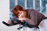 Mature woman napping on an exercise bike