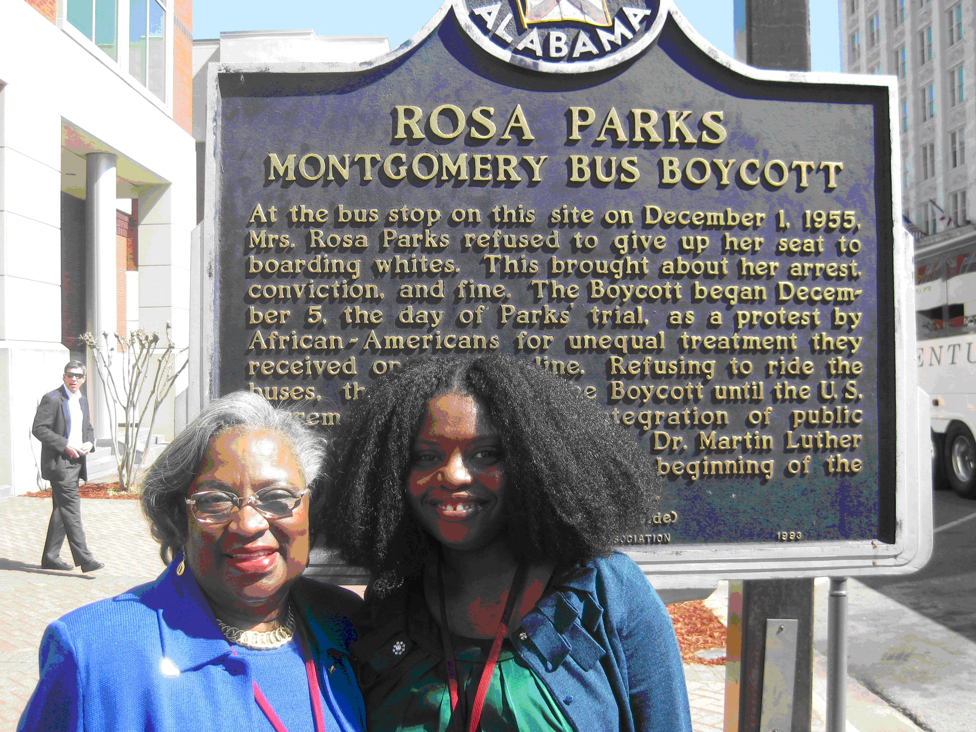 Picture of Juanita Abernathy (left) and Acacia Bamberg Salatti (right) standing in front of a memorial placard for the Rosa Parks Montgomery Bus Boycott in Montgomery, Alabama.
