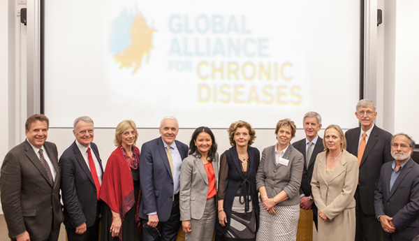 Group of people in suits standing in front of a screen that says Global Alliance for Chronic Diseases