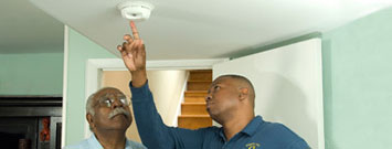 Photo: Man showing a fire detector to an elderly man