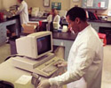 Man in lab coat standing at computer, representing Health Professionals