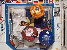 Bowling-ball-size yellow, red and blue robots float on the space station