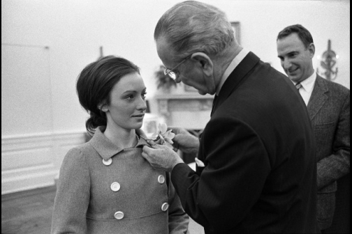 President Lyndon B. Johnson pins a flower on the lapel of figure skater Peggy Fleming