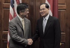 Secretary Locke and Minister Lim shaking hands in front of their countries' flags. Click for larger image.