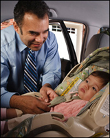 Photo: A father securing his child in a safety seat.