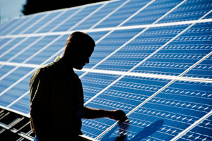 Photo of a male silhouetted against a solar array.