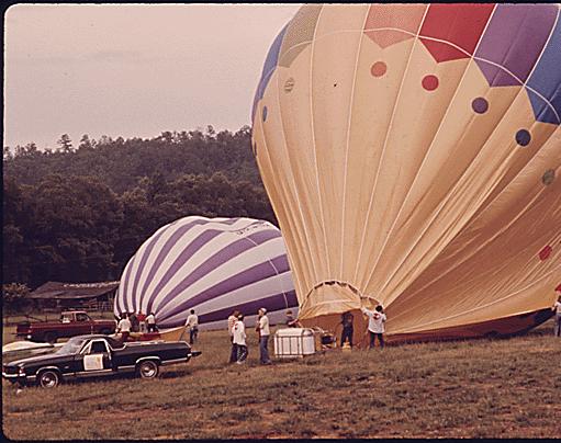 Hot air balloons being inflated with propane burners outside of Helen, Georgia, near Robertstown for the second annual Helen to Atlantic ocean balloon race. The competition began outside of town in an area being developed by a corporation as a second alpine village. Helen was a typical small mountain community until 1969 when town officials, businessmen and residents endorsed renovation of the business district with a Bavarian alpine motif, 05/1975 Documerica by Al Stephenson.
