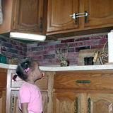 toddler girl looking up at locked cabinet