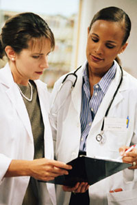 Tow medical staffers conferring over a clipboard.